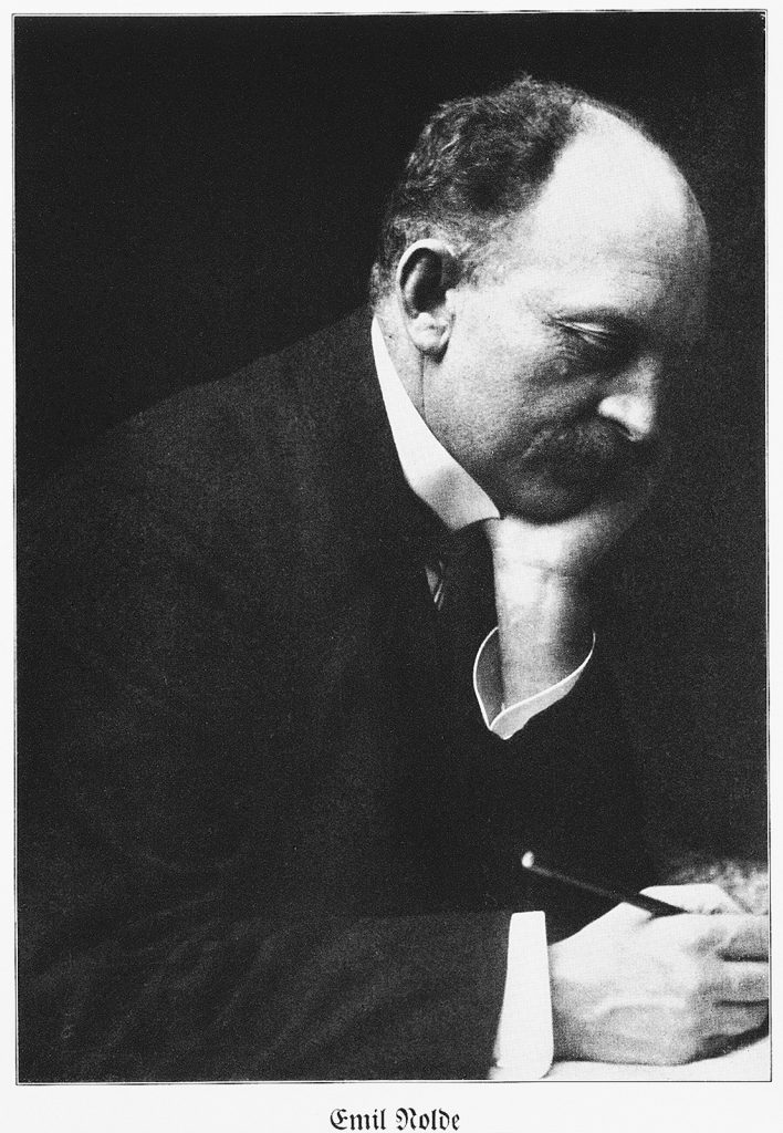 Schwarz-Weiß-Porträt von Emil Nolde im Profil; er stützt den Kopf nachdenklich auf die Hand und hält einen Stift.