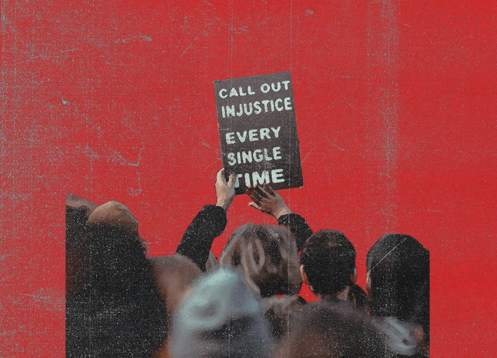 Eine Menschenmenge vor rotem Hintergrund hält ein Schild hoch mit der Aufschrift: „CALL OUT INJUSTICE EVERY SINGLE TIME“.